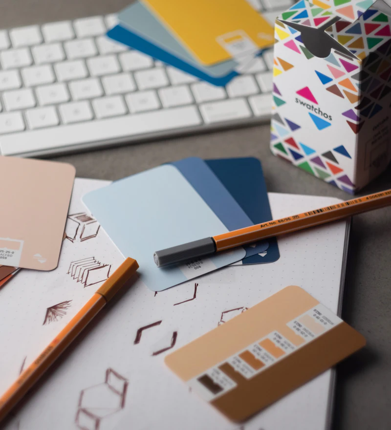 Mesa de trabajo con muestras de color, rotuladores y bocetos de identidad visual